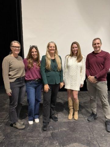 Five people standing together on a stage