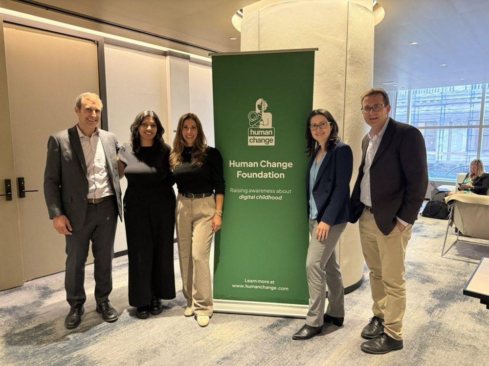 Five people standing beside a Human Change Foundation banner at a UN General Assembly event